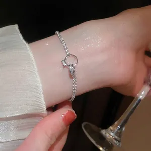 Minimalist silver knot bracelet with a sparkling zircon ring detail on a woman's wrist