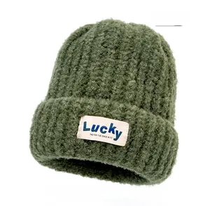 Detailed view of dark green thick knit beanie with Lucky textile patch and soft wool texture