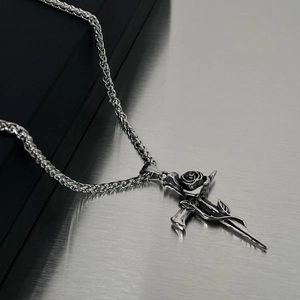 Vintage silver gothic cross necklace with rose detail on a textured metal background