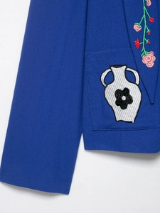 Detailed close-up of intricate floral embroidery on royal blue hooded jacket fabric