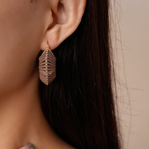 Close-up of brown textured leather geometric earrings on model with gold metal clasps