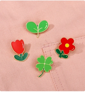Détail de pin's plantes en émail avec trèfle et tulipe sur tissu denim rose