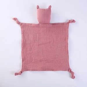 Detail of dusty pink muslin baby comforter with cat head design and knotted corners