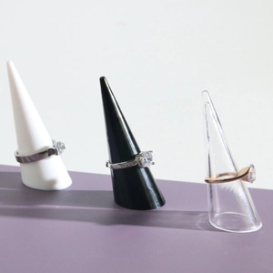 Macro view of crystal solitaire rings on white, black, and clear cone display stands