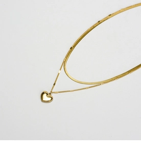 Macro view of double-layer gold snake chain and glossy heart pendant details