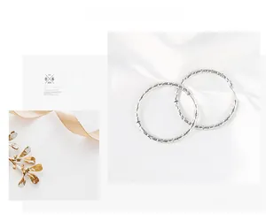 Detail of silver hoop earrings with hammered texture on white silk background