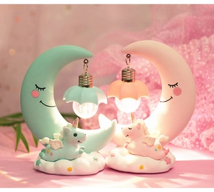Detail of unicorn moon night lights in mint green and pink resin with glowing LED bulbs
