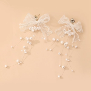 Boucles d'oreilles nœud en dentelle avec strass et glands en perles sur fond pêche doux