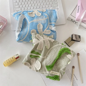 Detail of floral lace embroidery and soft tassels on premium cotton linen makeup bags