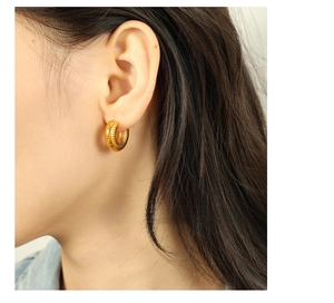 Macro detail of gold-plated 18K titanium steel hoop earring with textured stripe finish
