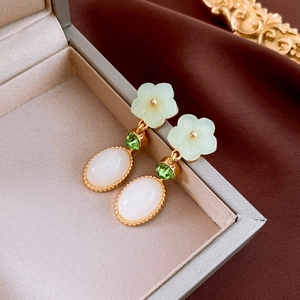 Detail of floral drop earrings with resin petals and faux jade stone on jewelry box