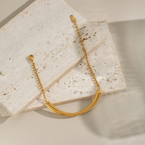 Minimalist gold bar pendant bracelet on stone pedestals for an elegant luxury aesthetic