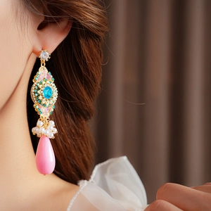 Gros plan de boucles d'oreilles vintage avec pierres bleues et perles roses en goutte