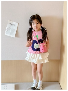 Pink cherry print bucket bag with gold chain strap worn by a girl in a stylish outfit