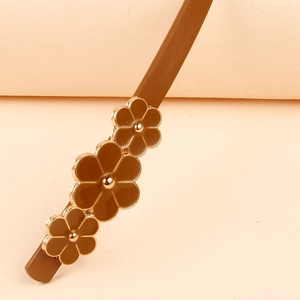 Close-up of brown floral accents with gold edges on a minimalist slim leather belt