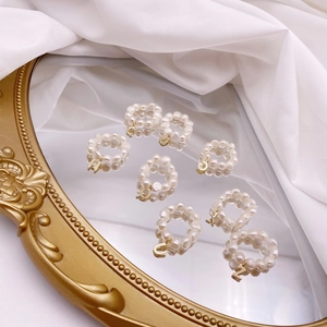 Detail of freshwater pearl elastic rings featuring golden letter charms on silk background