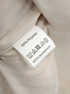 Detail view of clothing care label showing 100% polyester fabric and washing instructions