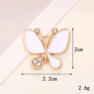 White butterfly charm with rhinestones and gold frame, measuring 2cm by 2.2cm