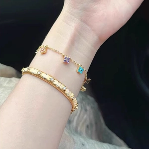 Bracelet trèfle doré de luxe et jonc à motif d'étoiles pour femme porté au poignet