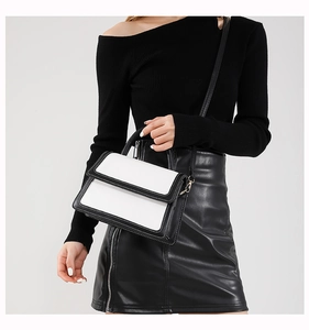 Detail of color-block crossbody bag with fine white stitching and matte leather texture