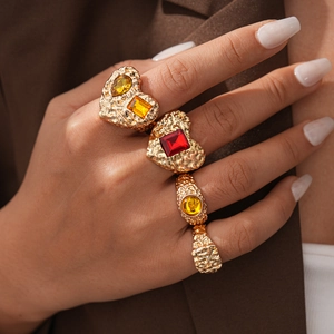 Close-up of vintage gold chunky rings with red and yellow resin gemstones on model hand