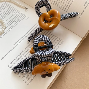 Gros plan de pinces à cheveux en forme de croissant et bretzel sur un fond de livre d'art