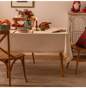 Detail of beige linen textured tablecloth featuring delicate lace edges in a festive setup