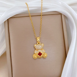 Golden titanium steel necklace with sparkling crystal bear pendant and red clover detail