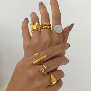 Detail showing a stack of gold-plated rings with lava texture and pearl inlay on hand