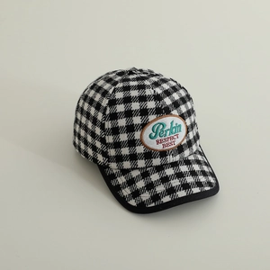 Close-up of black and white checkered fabric and embroidered oval patch on baseball cap