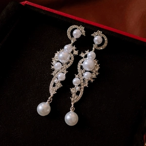 Macro shot of silver pearl drop earrings with rhinestones in a black velvet jewelry box