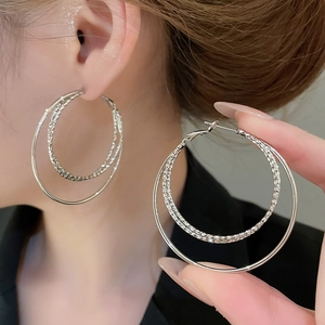 Detailed close-up of double-layered silver hoop earrings featuring textured metal finish