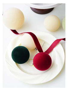 Detailed close-up of flocked Christmas balls in green, red, and cream on a white plate