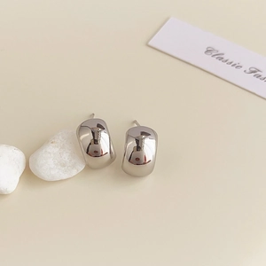 Macro detail of polished silver U-shaped hoop earrings with a minimalist geometric design