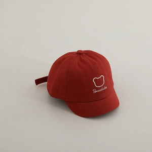 Détail d'une casquette bébé rouge en coton avec un ours blanc brodé au style minimaliste