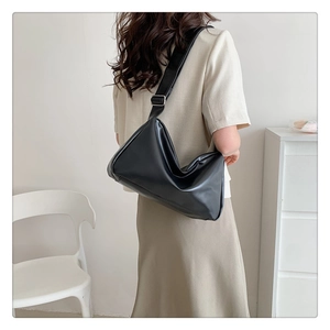 Black leather hobo bag with adjustable wide strap shown on a model from a side back view