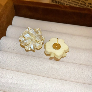 Macro shot of camellia flower earrings showing petal textures on beige velvet display
