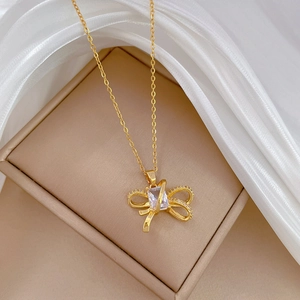 Macro detail of golden bow necklace pendant with crystal stones on white silk