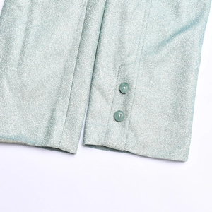 Gros plan des poignets d'un blazer métallisé vert menthe avec boutons ronds et tissu brillant