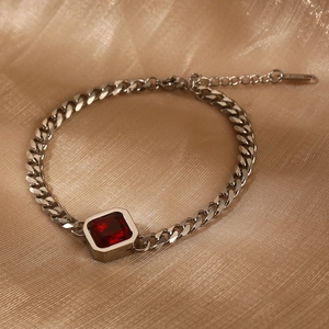 Silberne Panzerarmband aus Edelstahl mit rotem Zirkonia auf goldenem Seidenhintergrund