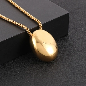 Macro shot of polished gold water drop pendant and box chain on black textured gift box