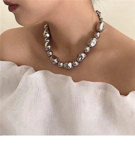 Close-up of irregular silver metal beads necklace on neck with liquid metal texture