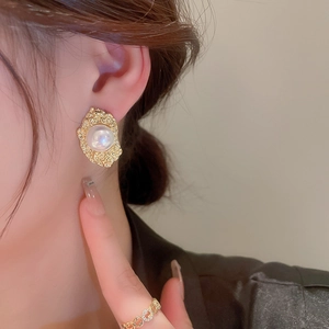 Close-up of vintage gold hammered earrings with white pearls and luxury ring details