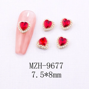 Macro detail of red heart crystal nail charm with pearl border on gold setting