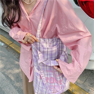 Detail of purple plaid canvas tote bag showing artistic text print and outer pocket