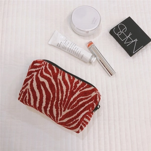 Detail of red zebra print velour makeup bag with cosmetics on a quilted background