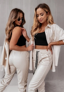 Set tre pezzi con top nero, pantaloni beige e camicia su modelle di moda