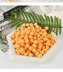 Gros plan de maïs soufflé en PVC orange réaliste empilé sur un plateau hexagonal blanc