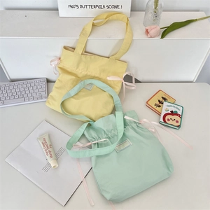 Detail of canvas tote bags with drawstring closure and pink ribbon bows in pastel colors