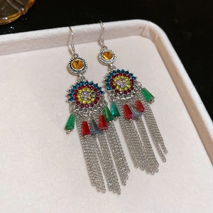 Detailed close-up of ethnic silver earrings with colorful rhinestones and fringe tassels